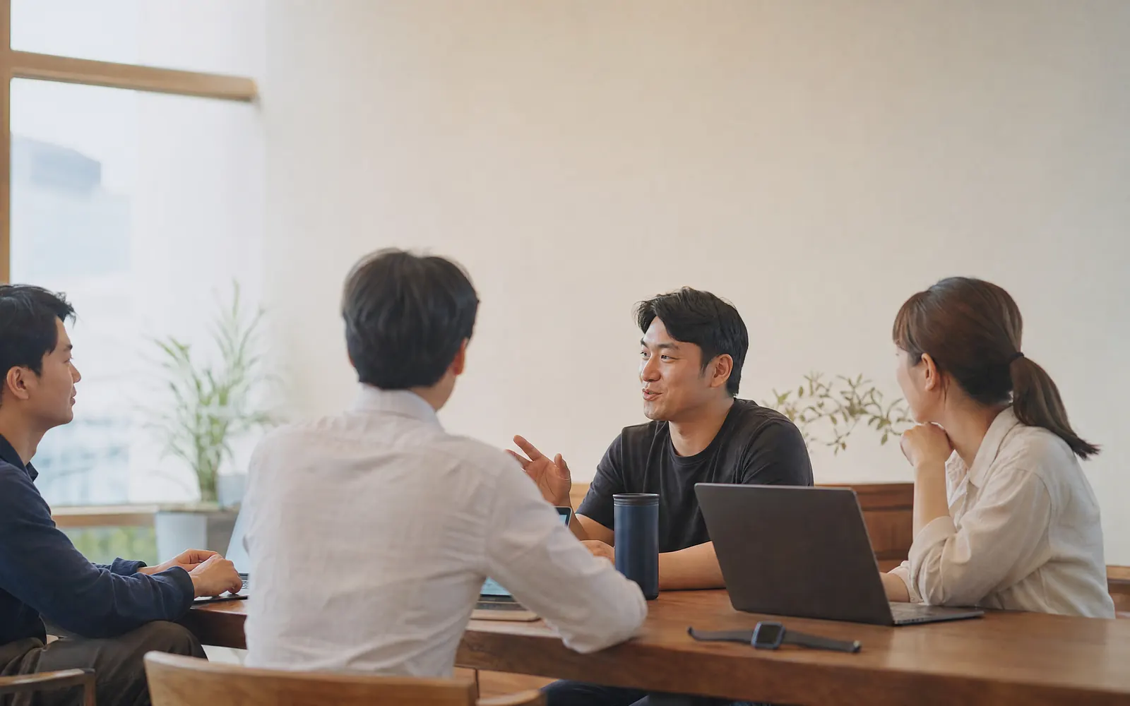 자연광이 드는 회의실에서 마주 앉아 이야기를 나누는 두 사람